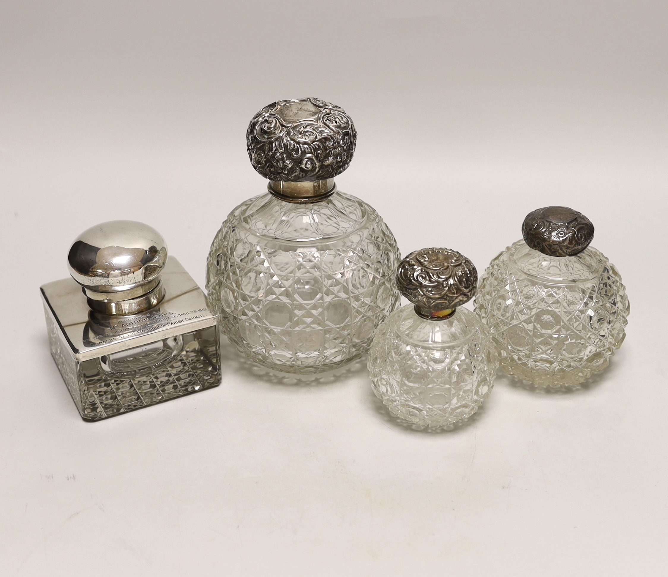 A George V silver mounted glass inkwell and three silver mounted cut glass scent bottles, largest 16cm (a.f.).